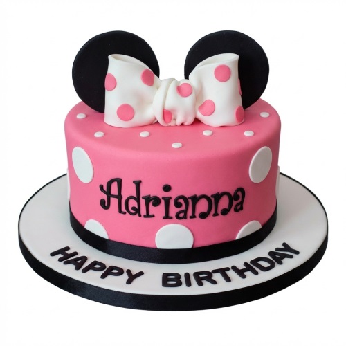 Pink Minnie Mouse themed birthday cake with black ears, white polka dot bow, and white polka dots.