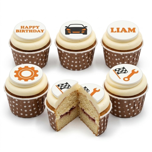 Six cupcakes with white frosting and brown polka dot wrappers, topped with edible discs featuring a black car, racing flag, wrench, gear, and 'Happy Birthday' message.