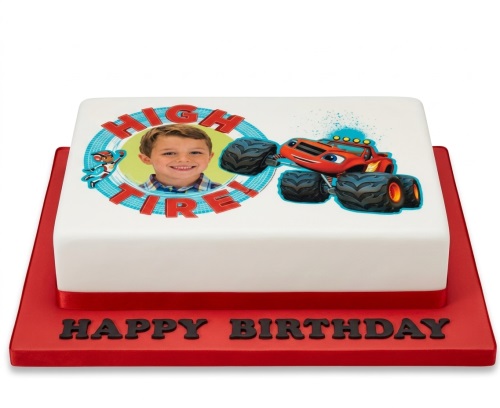 Square white birthday cake with Blaze the Monster Machine, a character, and a custom photo, on a red board with 'Happy Birthday'.