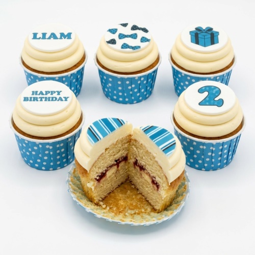 Set of blue and white boys birthday cupcakes with bow ties, gift box, and custom age topper.
