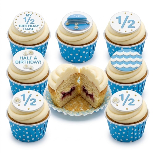 Collection of half birthday cupcakes with blue and white polka dot cases and '1/2' themed toppers, some with small white roses and gold pearls.