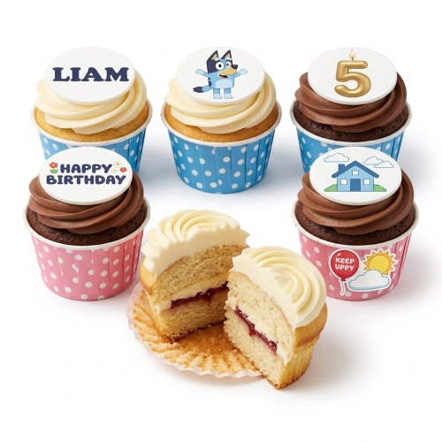 Bluey character, house, and custom message birthday cupcakes with blue and pink cases, one cut open to show jam filling.