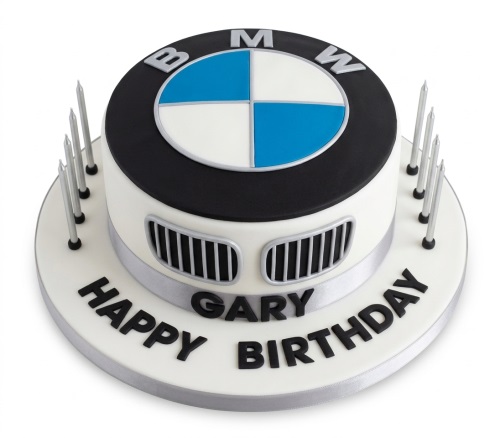 Round white and black BMW birthday cake with blue and white logo, car grill details, silver ribbon, and personalised message.