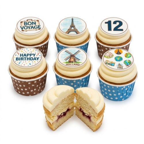 A set of vanilla cupcakes with white frosting and edible travel-themed toppers, including Bon Voyage, Eiffel Tower, Holland windmill, Happy Birthday, and the number 12. One cupcake is cut open showing jam filling.