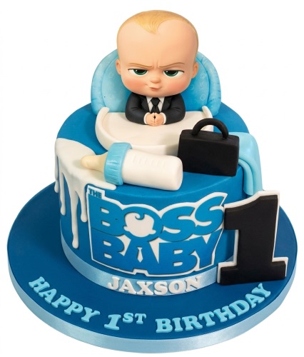 Blue and white Boss Baby themed 1st birthday cake with figurine, baby bottle, and briefcase.