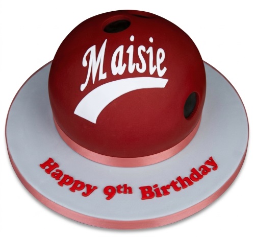 Red bowling ball cake with white stripe and personalised name on a grey board.