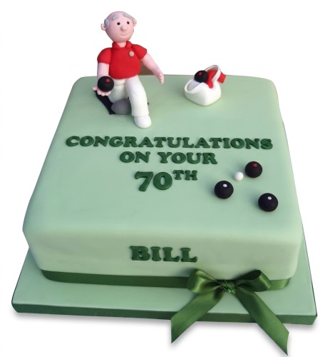 Green square lawn bowls birthday cake with a male bowler figure, bowls, and a green ribbon.