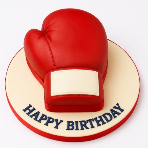 Red boxing glove shaped birthday cake on a round board with 'Happy Birthday' message.