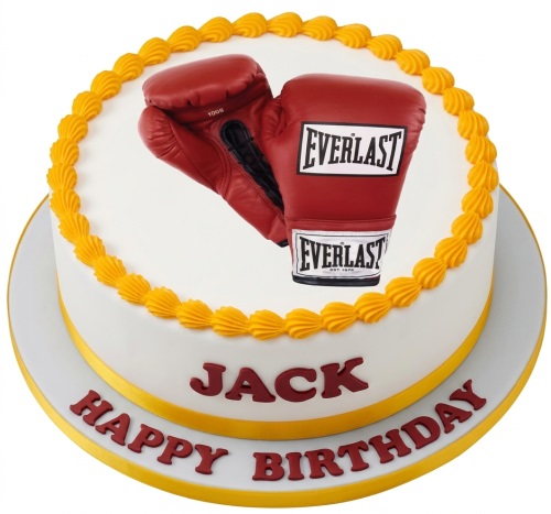 Round white birthday cake with red boxing gloves and yellow piping, for a custom name.