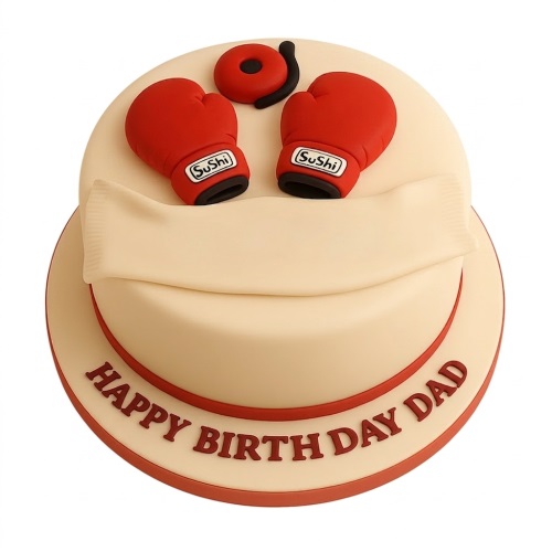 Cream round birthday cake decorated with red boxing gloves, a red and black bell, and a blank banner.