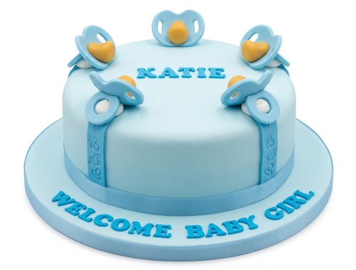 Light blue round cake decorated with blue pacifiers and a baby-themed ribbon, with space for custom text.