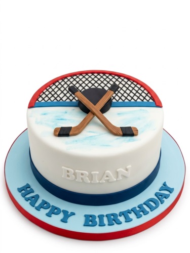 Round white ice hockey themed birthday cake with edible sticks, puck, and goal net, on a blue board with a custom message.