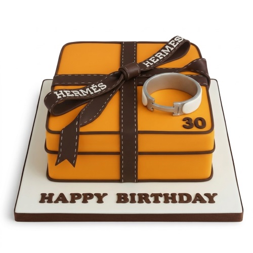 Orange Hermes gift box birthday cake with brown ribbon, replica bracelet, and custom age topper.