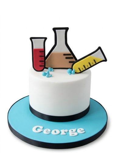 White round cake with edible science lab equipment decorations including test tubes and beakers, on a blue cake board.