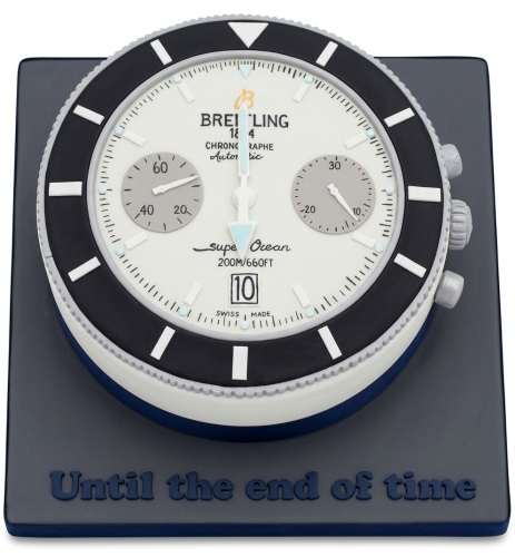 Round Breitling Superocean watch themed birthday cake with white, black, and grey details on a dark grey base with 'Until the end of time' message.