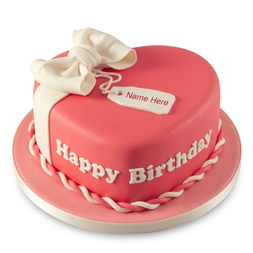 Pink heart-shaped birthday cake with a white bow, ribbon, and 'Happy Birthday' text, featuring a customisable name tag.