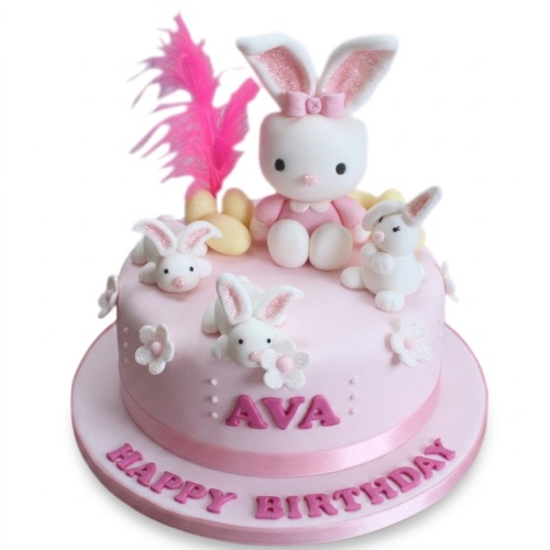 Pink round birthday cake with a large bunny figure, smaller bunnies, and white flowers.