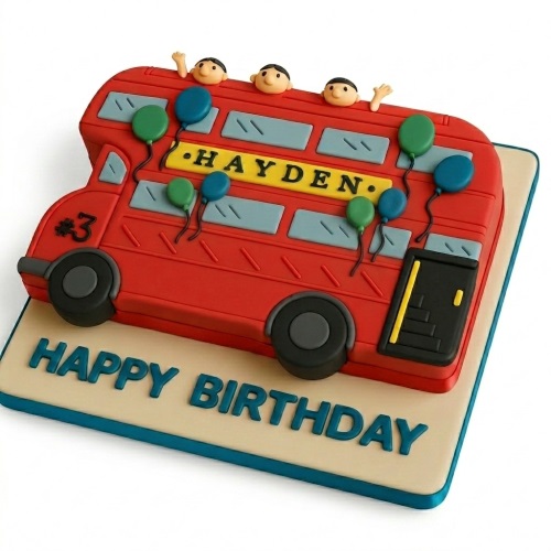 Red double decker bus shaped birthday cake with small figures, balloons, and 'Happy Birthday' message on the board.