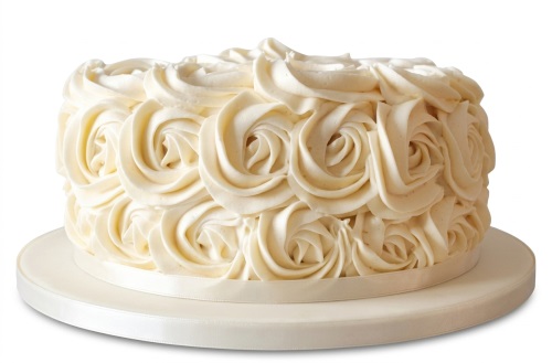 Round cream cake with piped buttercream rosettes and a satin ribbon.
