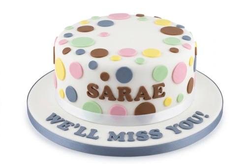 Round white cake with colourful pastel polka dots, a personalised name, and a custom farewell message on the cake board.