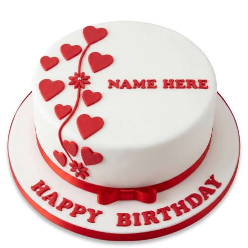 White round birthday cake with red hearts, red ribbon, and space for a custom name.