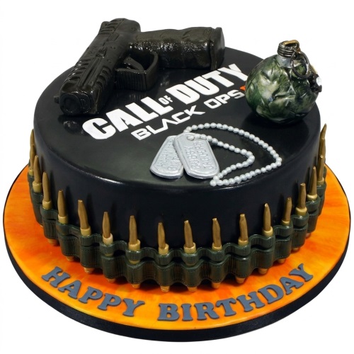 Round black Call of Duty Black Ops birthday cake with edible gun, grenade, dog tags, and bullet belt.