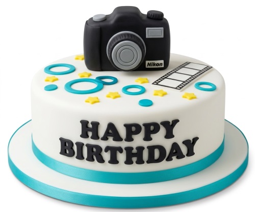 White round birthday cake with a black camera topper, film strip, yellow stars, blue rings, and 'Happy Birthday' message.