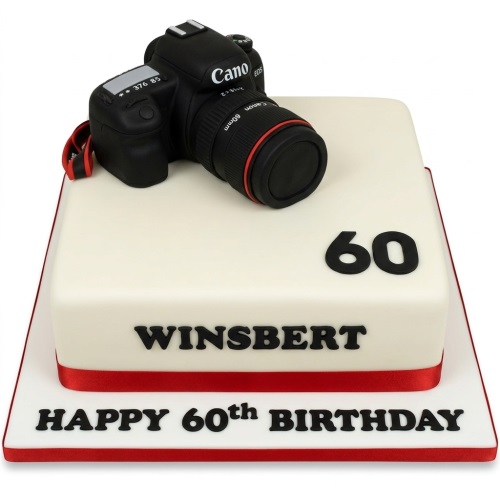 Square cream birthday cake topped with a black DSLR camera model, red ribbon, and custom age numbers.