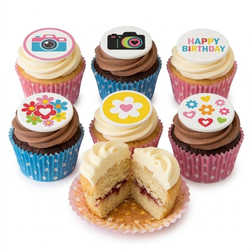 A selection of birthday cupcakes with camera, floral, and 'Happy Birthday' edible toppers, some with vanilla and some with chocolate frosting.