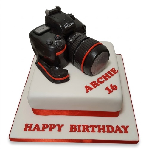 Two-tier white birthday cake with a black DSLR camera topper and red accents.