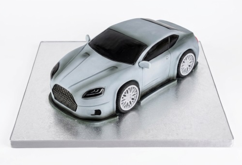 Grey sports car shaped birthday cake on a silver cake board.