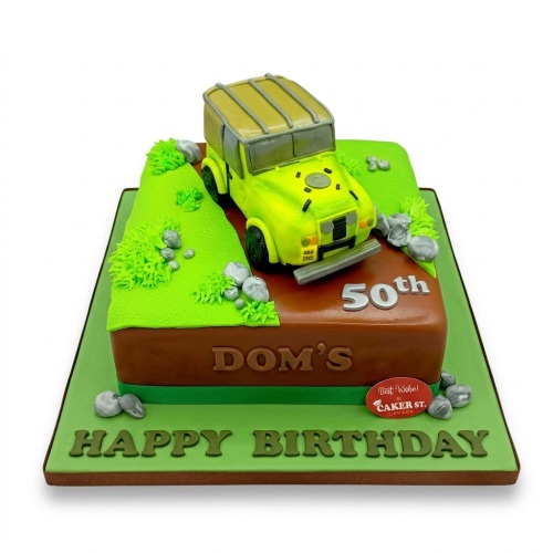 Off-road car birthday cake with green hills, rocks, and custom age and name.