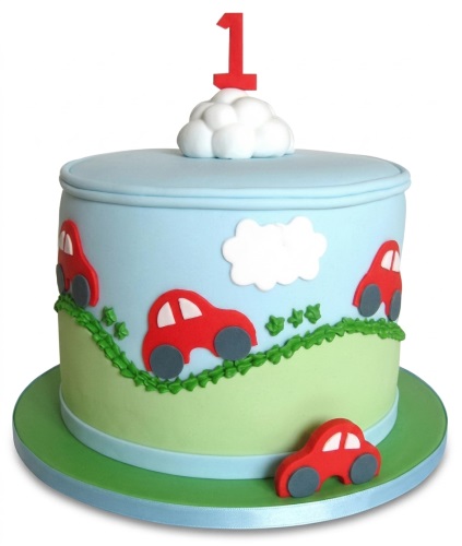 Round blue and green car themed birthday cake with red cars, white clouds, and a red number one topper.