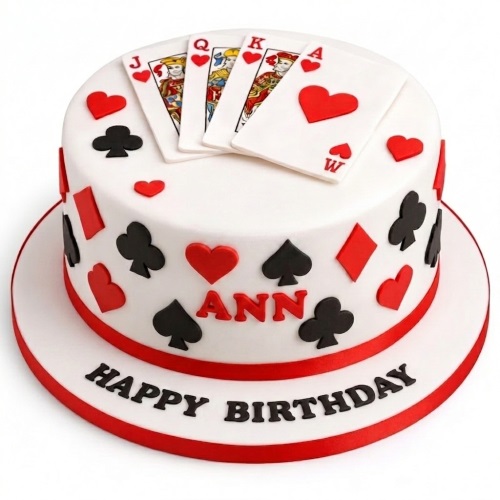Round white cake with playing cards, red hearts, black clubs, red diamonds, and black spades decorations.