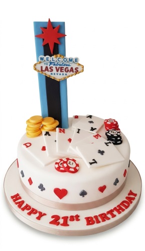 White round cake with Las Vegas sign topper, playing cards, poker chips, and gold coins.