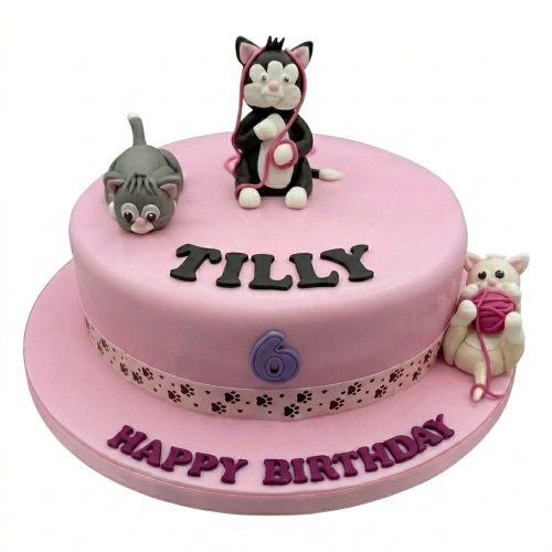 Two-tier pink birthday cake with three playful cat figurines, paw print ribbon, and custom age topper.