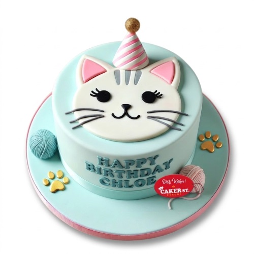 Cute cat face birthday cake with party hat, yarn balls, and paw prints on a light blue cake.