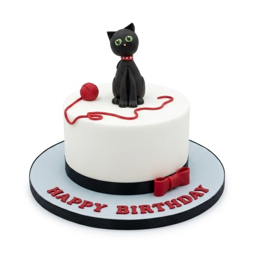 White round birthday cake with black cat figurine, red yarn, and "Happy Birthday" text.