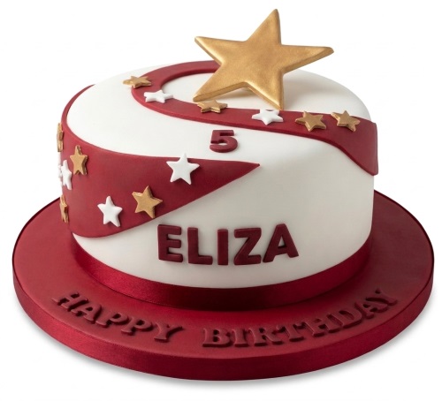Round white cake with red swirl, gold and white stars, and a large gold star topper on a red cake board.