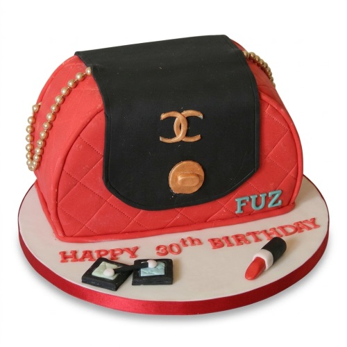 Red and black quilted Chanel handbag cake with gold logo, pearl chain, and edible makeup.