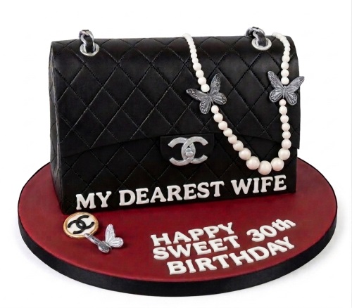 Black quilted Chanel style handbag cake with pearl chain, butterflies, and custom message.