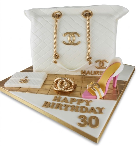 White quilted handbag cake with gold chain straps, gold logo, high heel shoe, and 'Happy Birthday' message.
