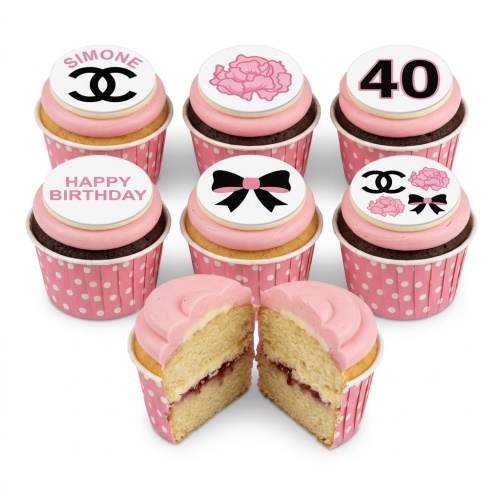 Set of six designer-inspired cupcakes with pink frosting, featuring fashion logos, pink flowers, and black bows on white toppers.