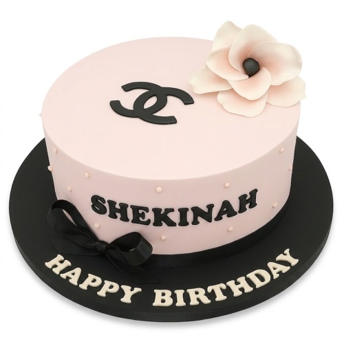 Round pale pink designer-style birthday cake with black logo, peach flower, and custom name.