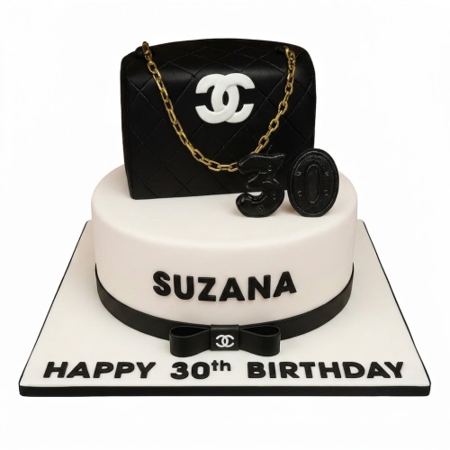 Two-tier black and white cake with Chanel style handbag, gold chain, and custom age topper.
