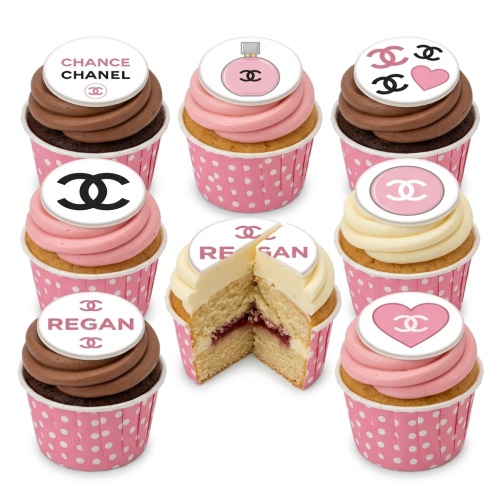 Assortment of Chanel theme cupcakes with pink, white, and chocolate frosting, featuring logo, perfume bottle, and heart toppers.