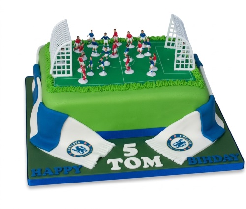 Green football pitch birthday cake with miniature players, goals, and a blue and white Chelsea FC scarf. Features a custom age and personalised name.