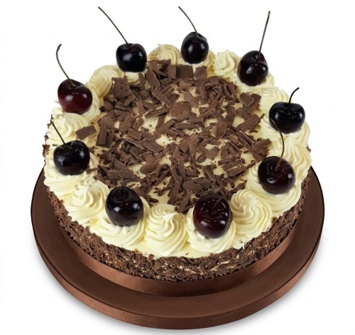 Round Black Forest cake with chocolate shavings, cream swirls, and whole cherries.