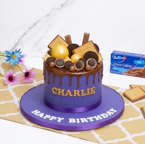 Purple chocolate drip birthday cake with biscuits, chocolates, and personalised name.