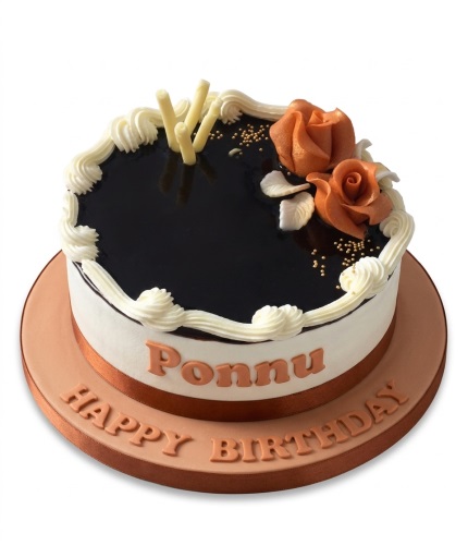 Round white birthday cake with dark glaze, orange sugar roses, gold sprinkles, and custom message.